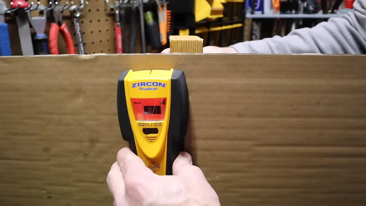 Stud finder being used on drywall showing LEDs and middle indicator