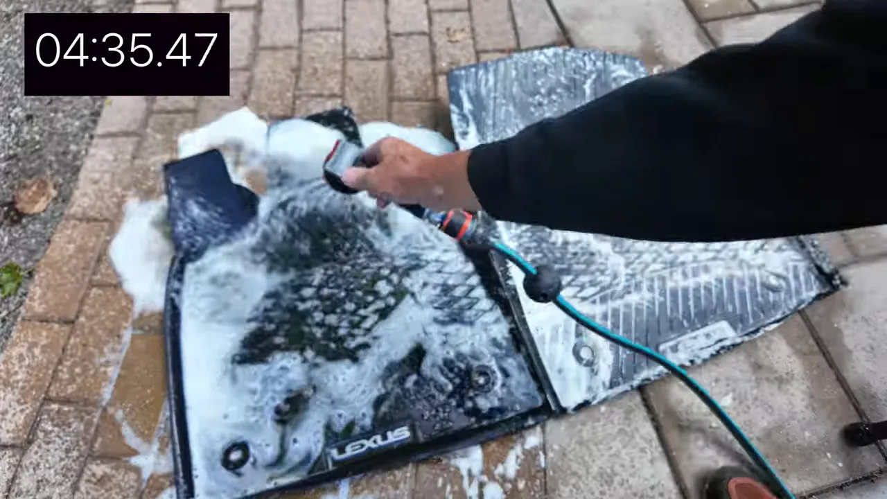 Rinsing foam and dirt off the rubber floor mat with a hose
