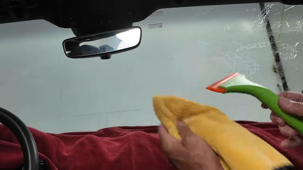 Using a plastic squeegee to remove soap and water from the windshield