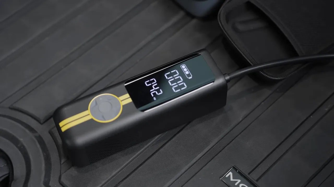 Fanttik portable air compressor on a Tesla all-weather trunk mat with tire pressure display illuminated