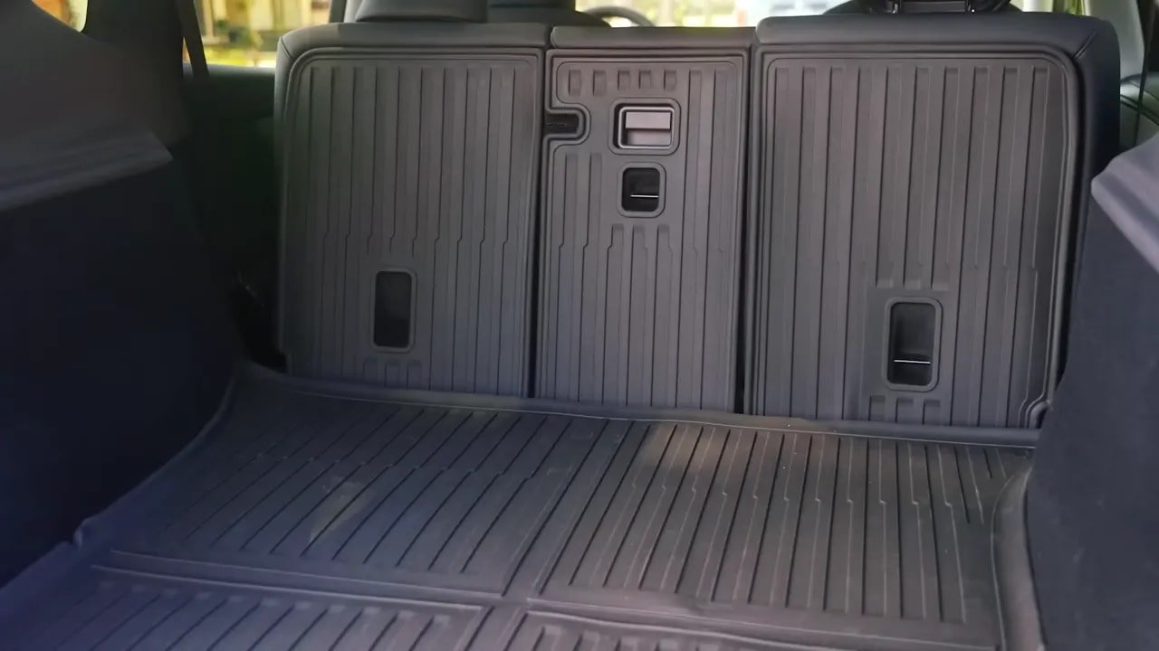 Tesla accessories for the Model Y cargo area with protective mats over the folded rear seats and floor