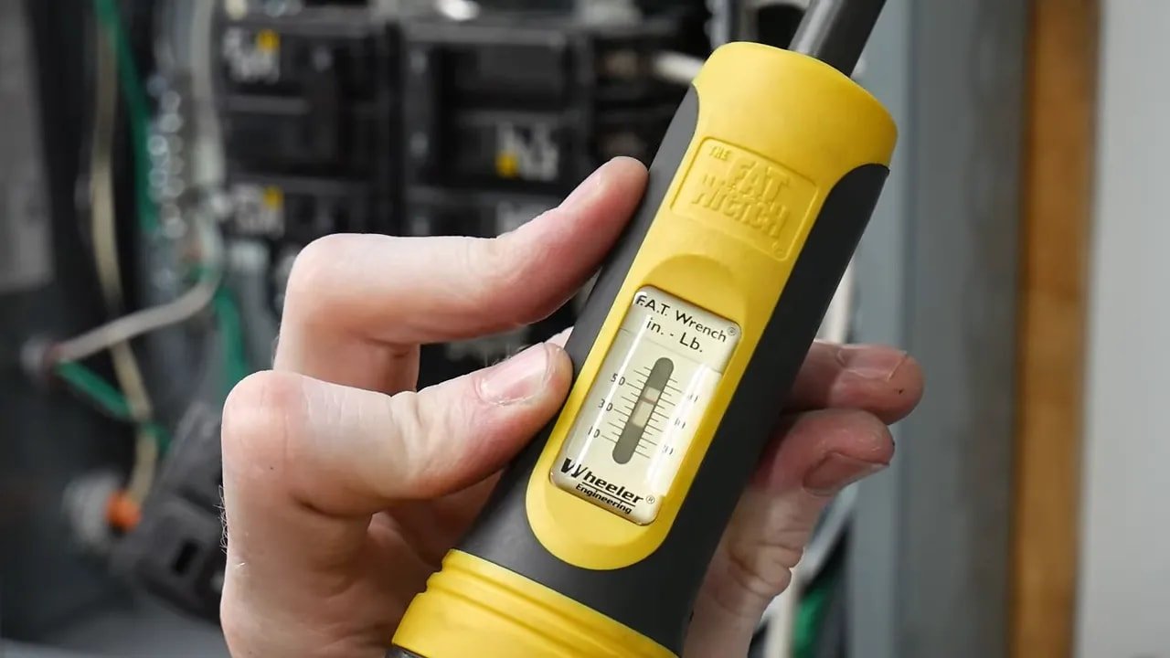 Yellow torque screwdriver display set near 25 inch pounds in front of an electrical panel